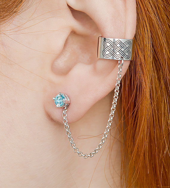 Silver Celtic chain ear cuff with blue stone stud, close-up on ear
