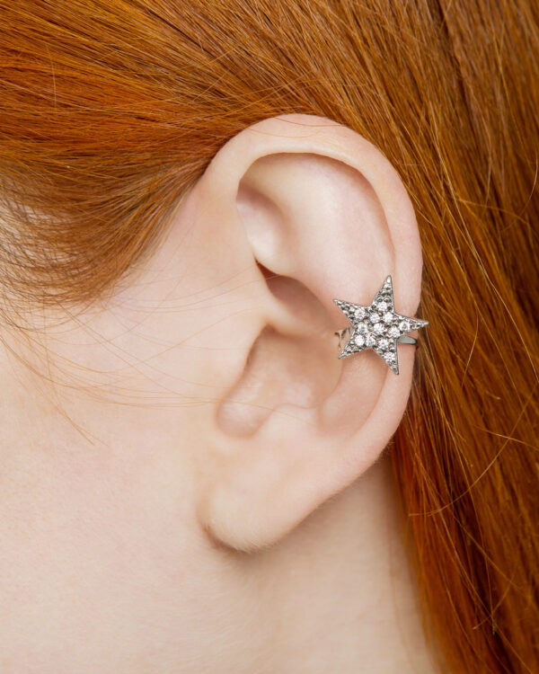 Silver star ear cuff with clear cubic zirconia on red-haired model’s ear, worn on middle cartilage without piercing.