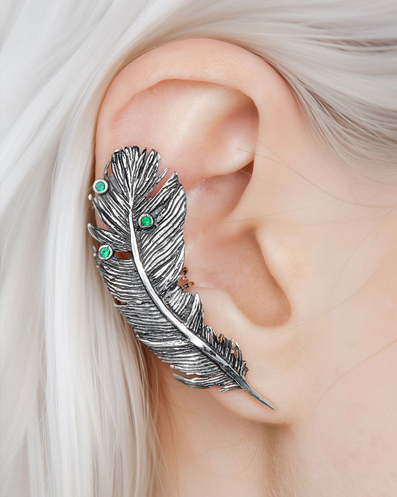 Silver feather ear cuff with green stones on model’s ear, no piercing needed.