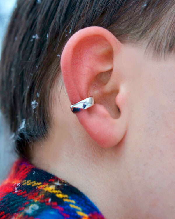 Sterling silver minimalist ear cuff worn in winter setting, close-up on ear