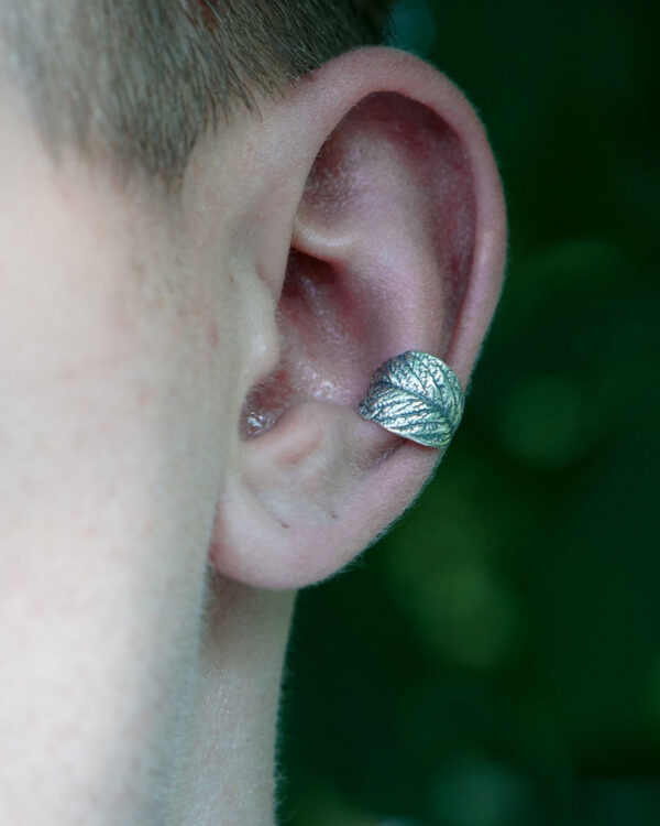 Sterling silver cartilage ear cuff with leaf design, worn on ear, outdoor setting, unisex jewelry, no piercing needed