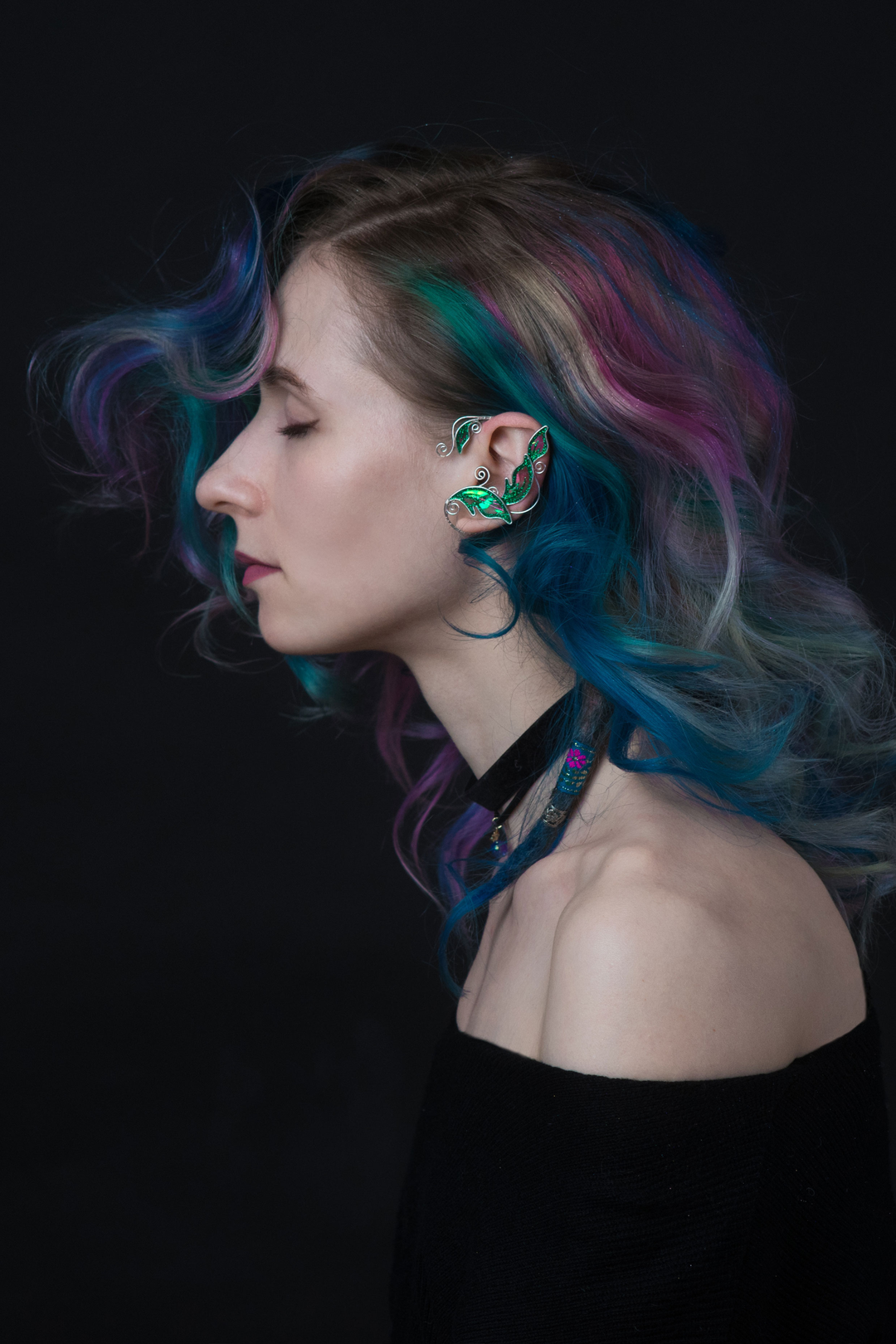 Emerald green elven leaf ear cuff worn by model with colorful hair on dark background, handmade fantasy jewelry