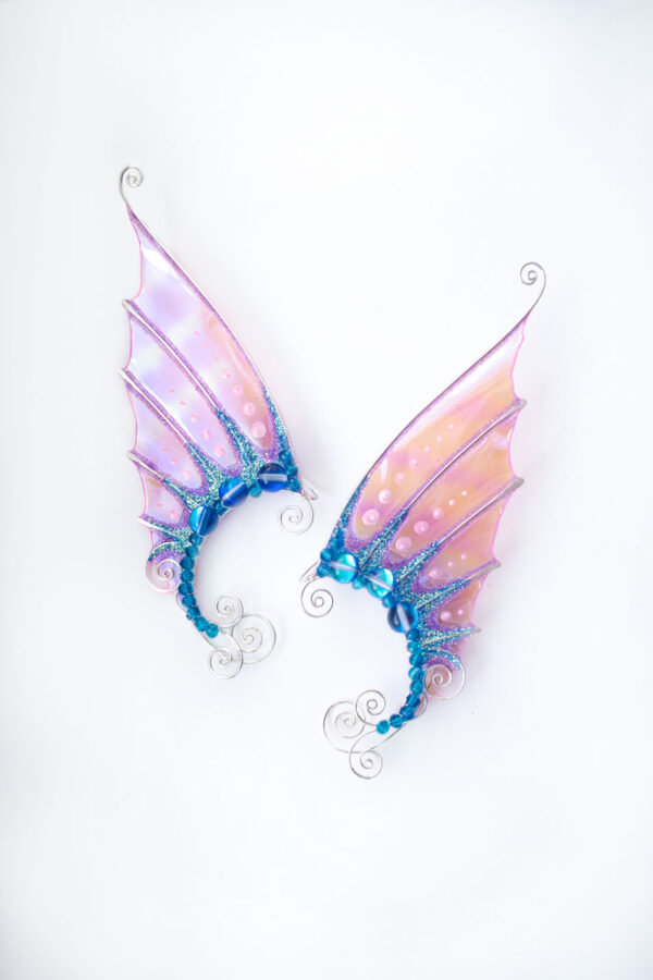 Pair of handmade pink and blue mermaid ear cuffs with glitter on white background