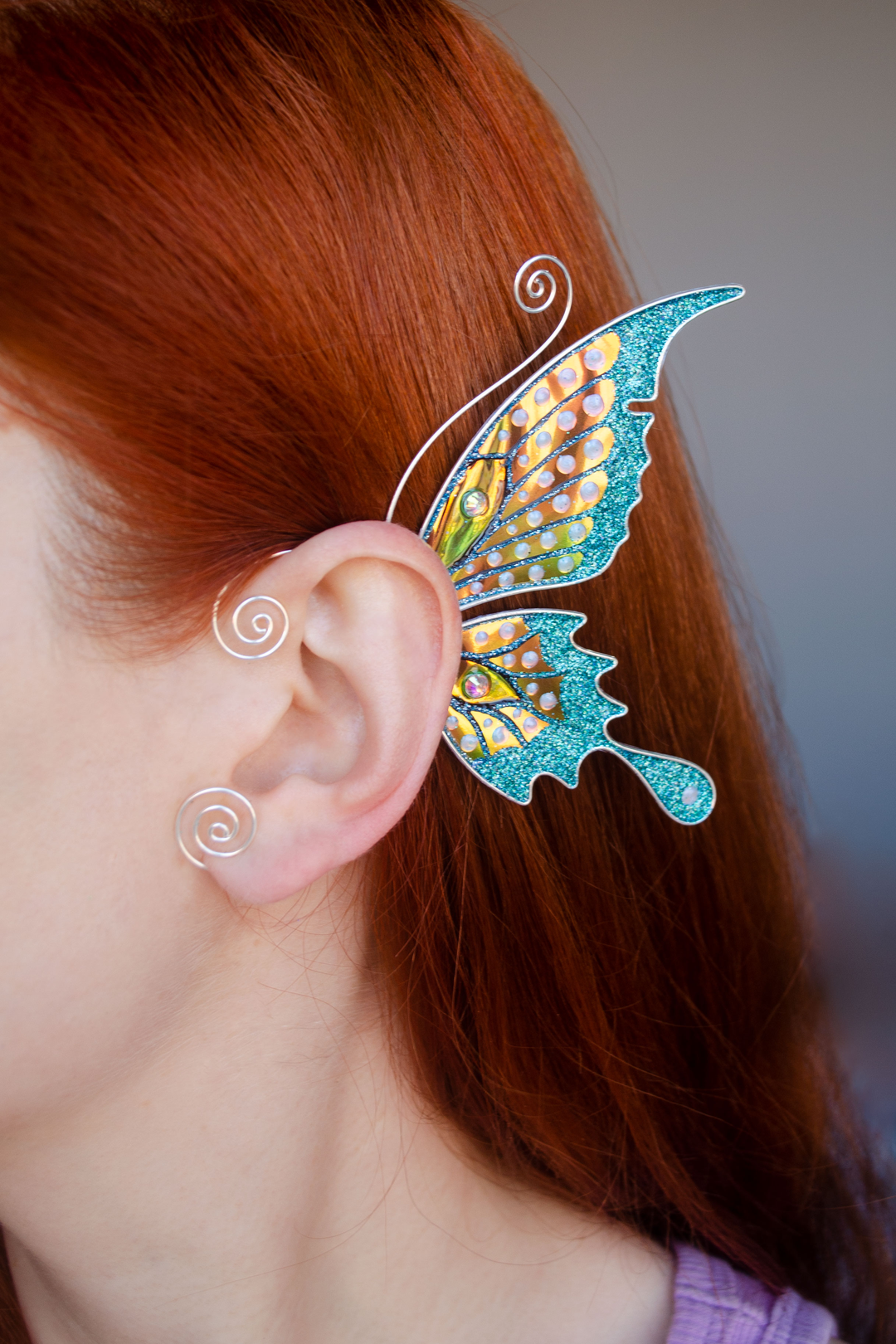 Butterfly ear cuff worn on red-haired model, handmade fairy wing earring with teal and gold details, no piercing needed