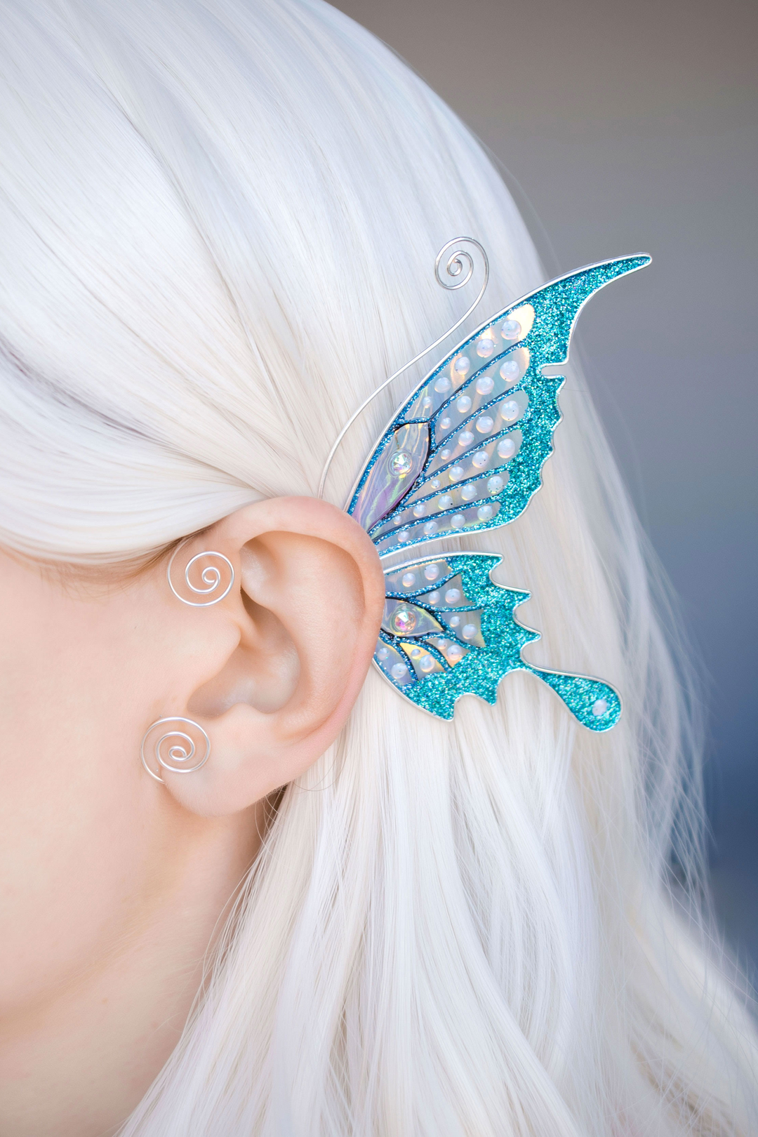 Handmade butterfly ear cuff on white-haired model, teal glitter fairy wing earring, no piercing needed