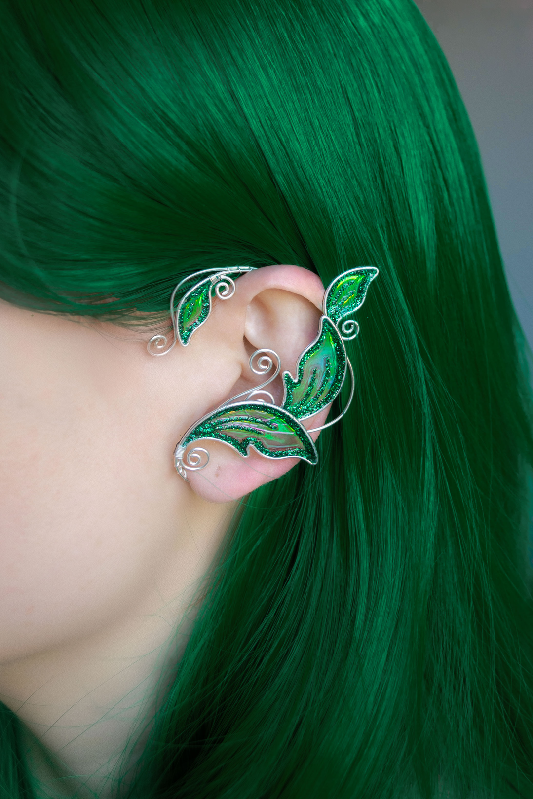 Emerald green elven leaf ear cuff worn on model with bright green hair, handmade no-piercing elf ear cuff