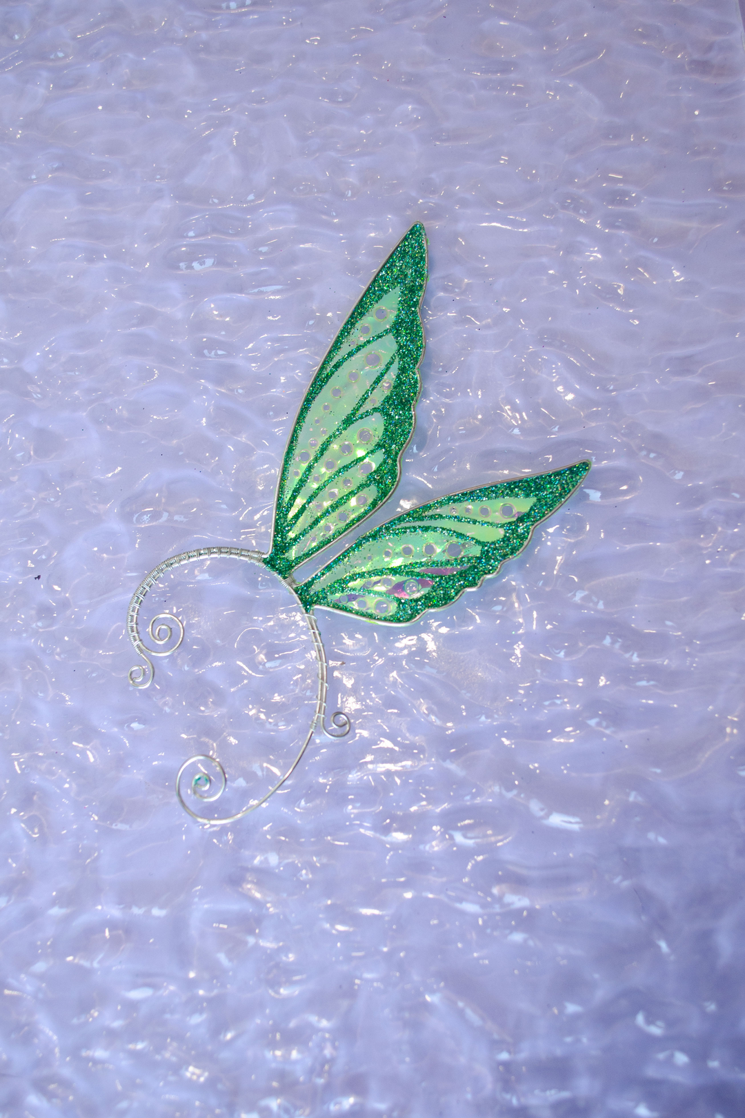 Fairy cosplay ear cuff, green, handmade, no piercing needed, fairy earring — green glitter wing cuff displayed on glossy white textured background.