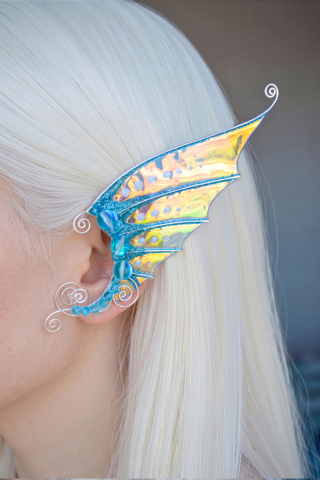 Golden and blue mermaid ear cuff worn by model with long white hair, handmade no-piercing earring