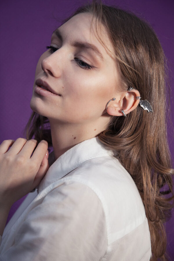 Silver dragon ear cuff on model with long brown hair and white blouse, fantasy earring without piercing