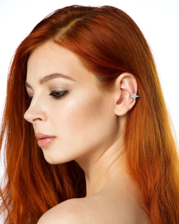Model with red hair wearing a silver star-shaped ear cuff with clear cubic zirconia.