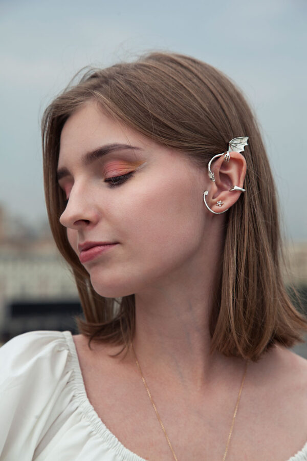 Sterling silver dragon ear cuff with wing detail, worn by woman with short brown hair and natural makeup