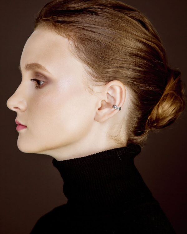 Silver Slavic ear cuff worn by female model in black turtleneck, side profile