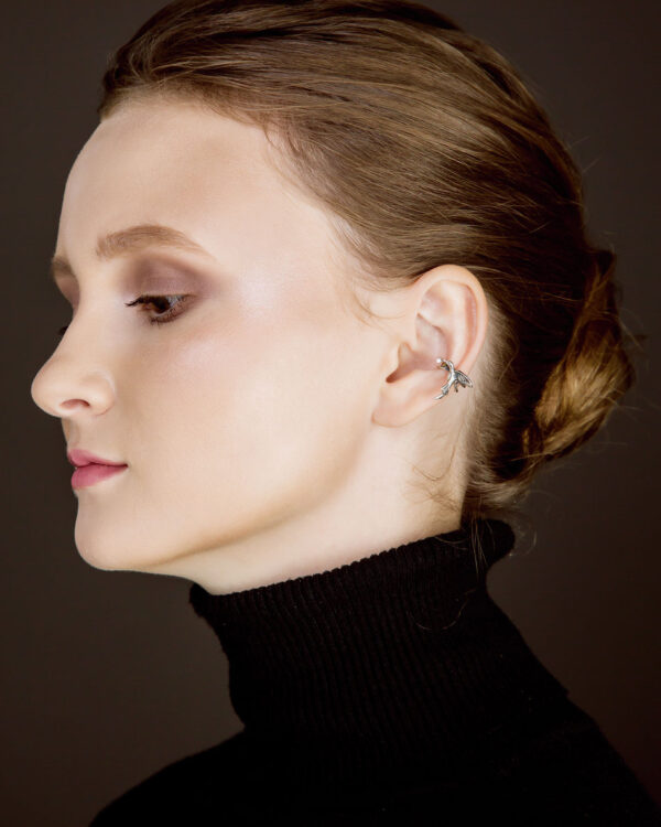 Silver hummingbird ear cuff with dewdrop stone on model’s ear