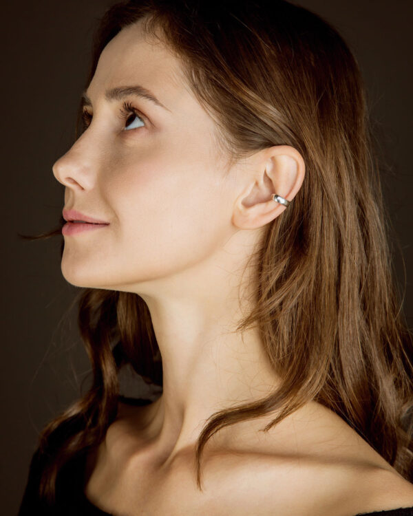 Sterling silver minimalist ear cuff worn by model with brown hair, side profile