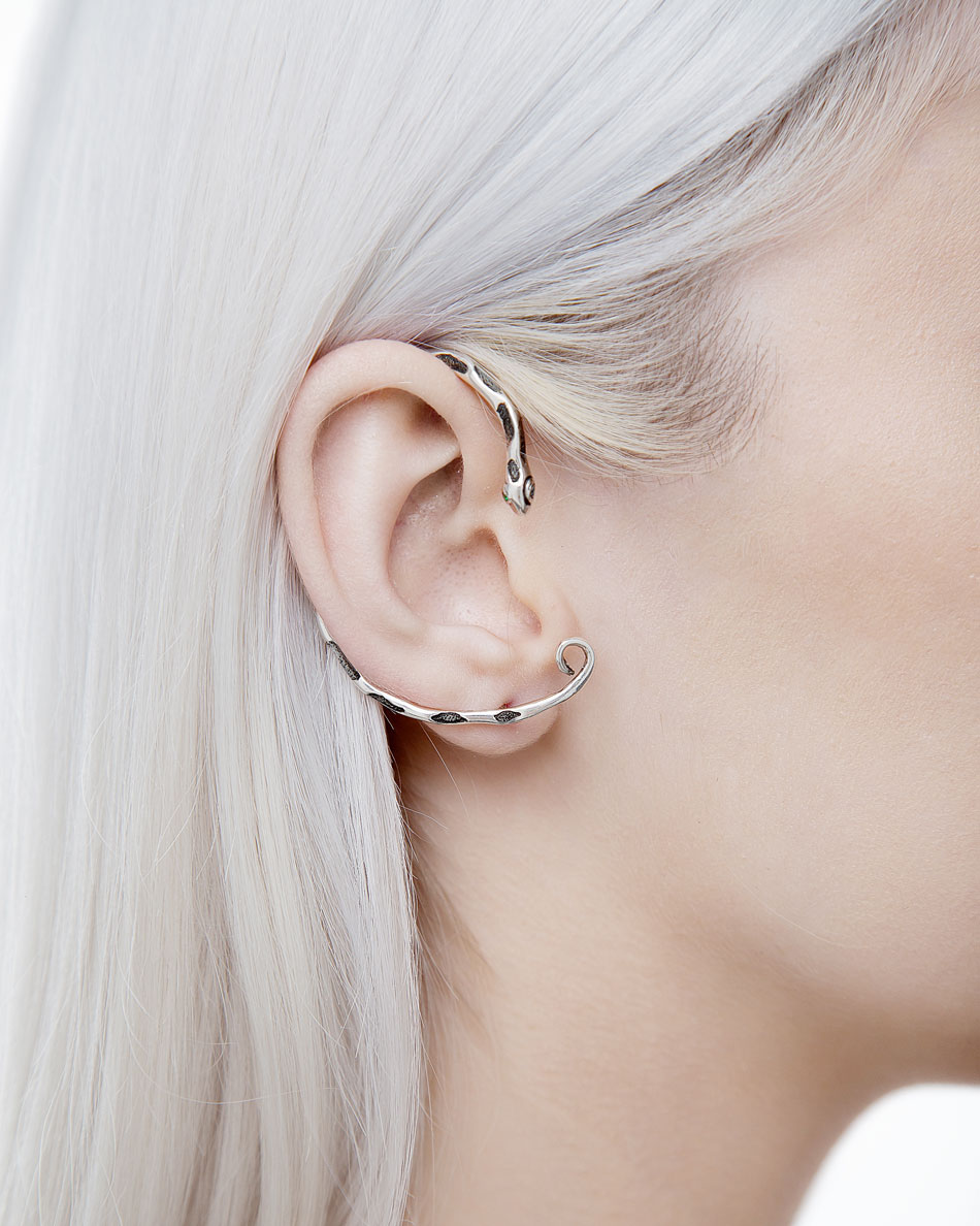 Snake-shaped ear cuff wrapping around ear with green eyes