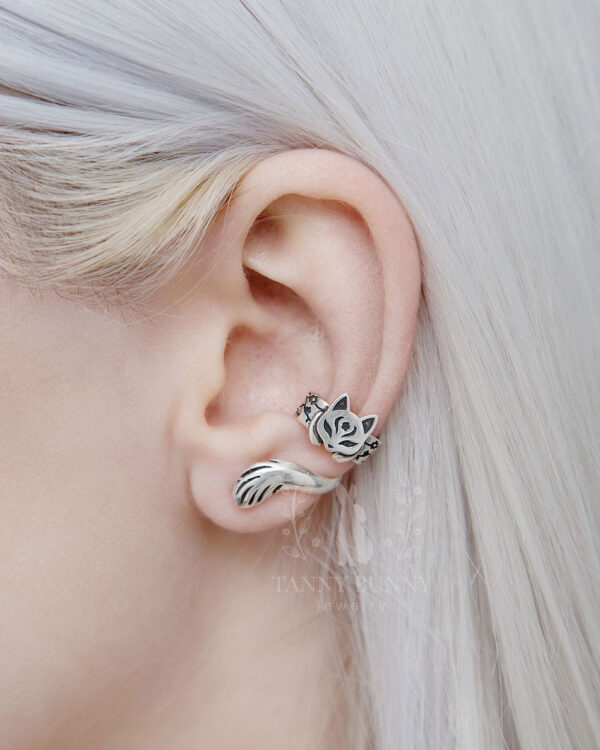 Japanese cat ear cuff in 925 sterling silver with floral details and curled tail, worn on ear by model with platinum blonde hair.