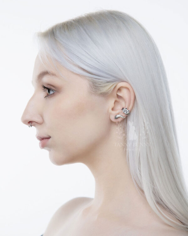Japanese cat ear cuff in 925 sterling silver with floral pattern and curled tail, worn by model with silver-blonde hair and nose piercing.
