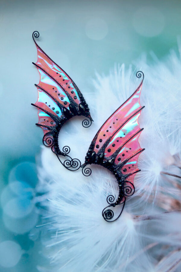 Black mermaid ear cuffs with iridescent red film on a dandelion background