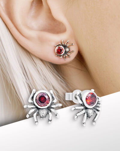 close-up of spider stud earrings worn on earlobe with red stones