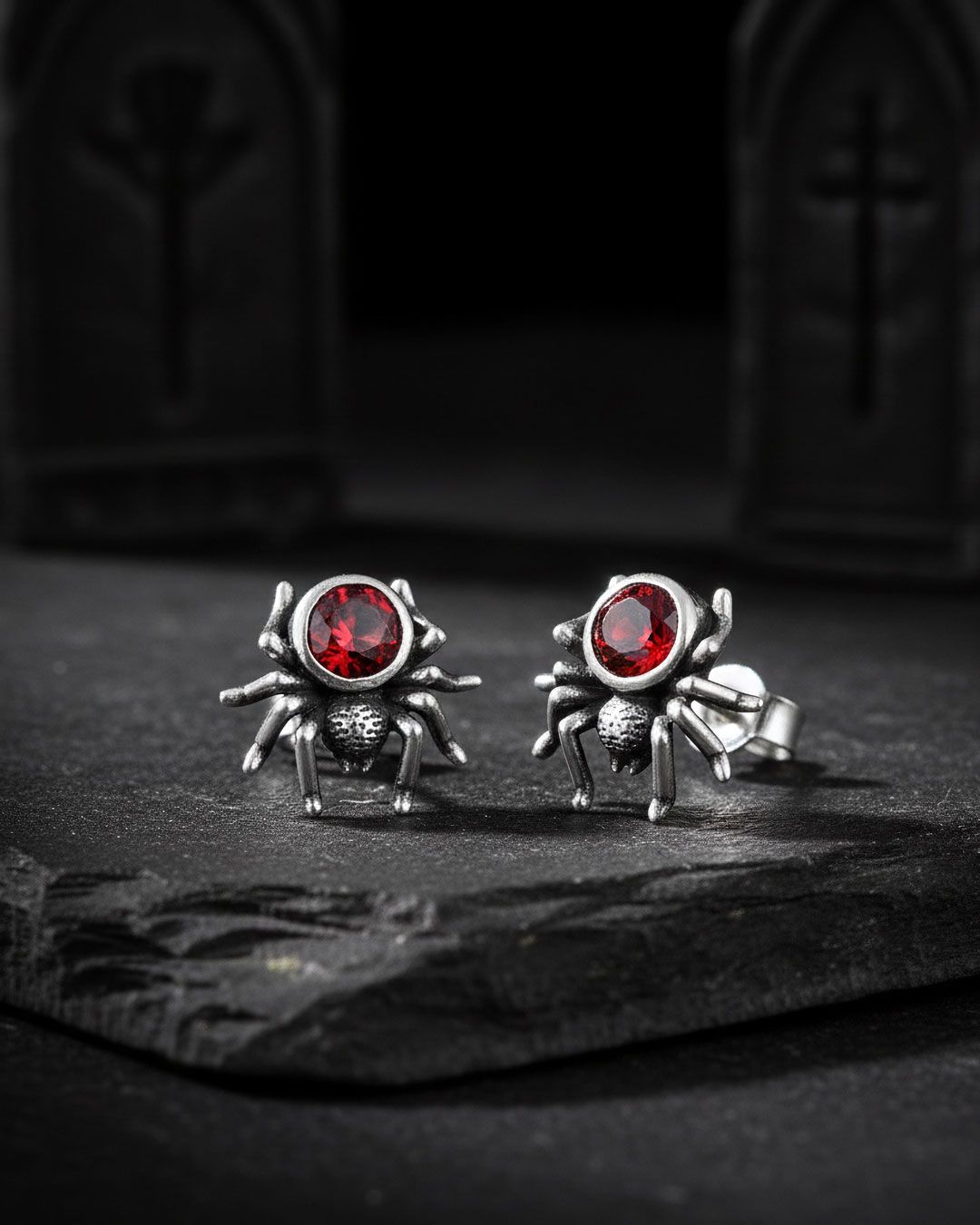 gothic-style product photo of spider stud earrings with red stones