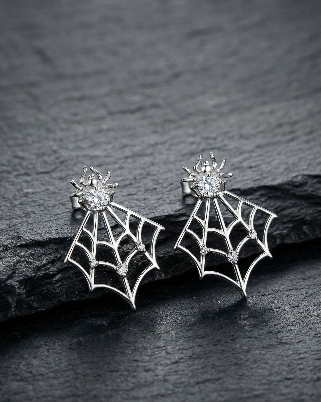 sterling silver spider web ear jackets with clear stones on black textured background