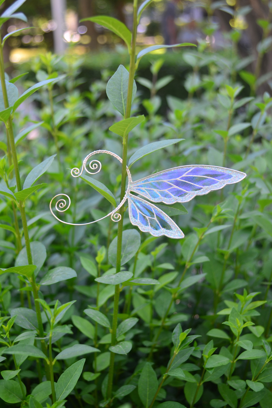 fairy wing ear cuff in white iridescent design displayed on green foliage