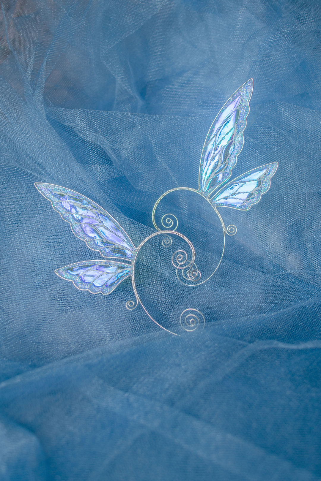 fairy wing ear cuffs in white iridescent finish displayed as a pair on blue fabric
