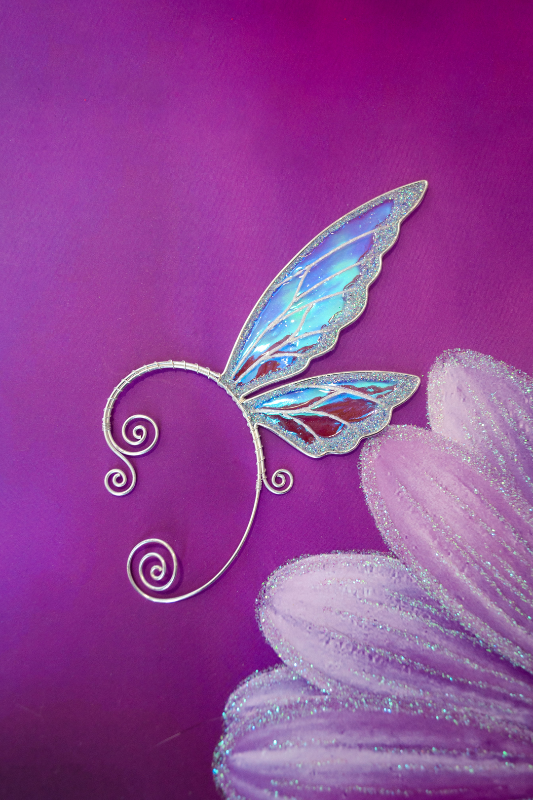 fairy wing ear cuff in white iridescent finish on purple background with painted flower