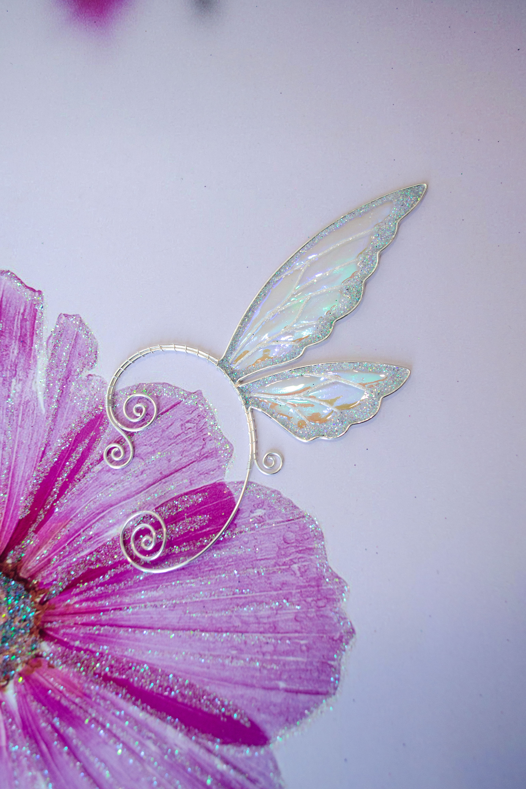 fairy wing ear cuff in white iridescent color on pink artistic background