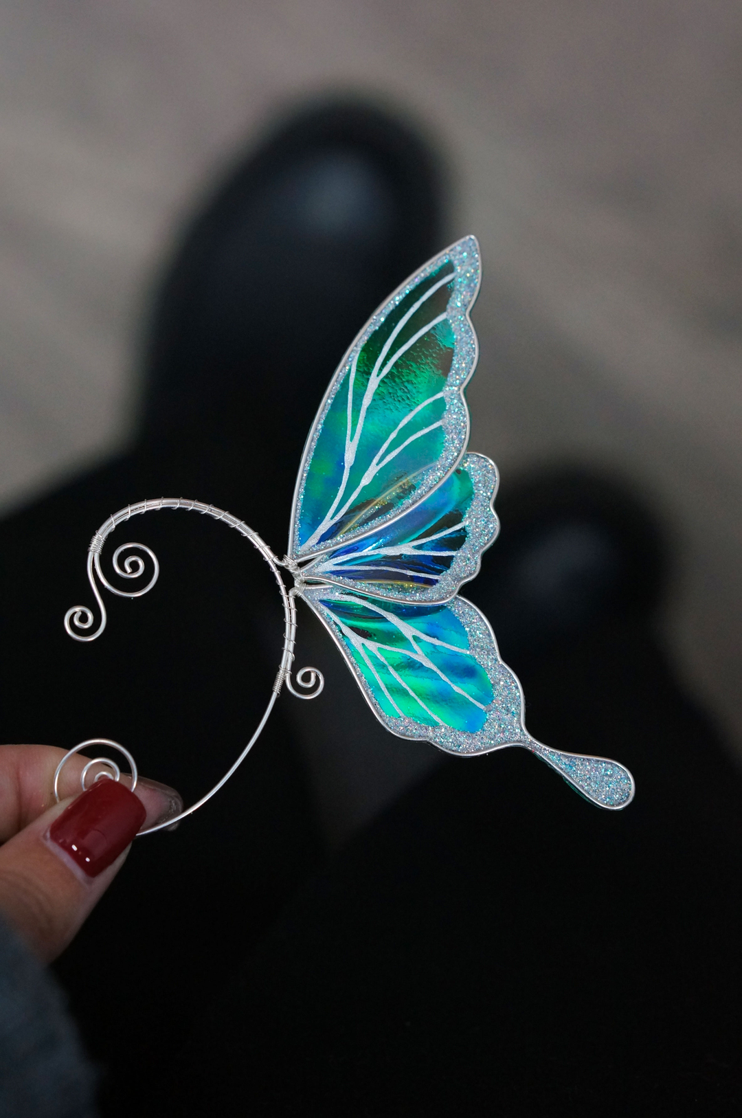 iridescent fairy wing ear cuff in green and white held in hand, handmade fairy ear jewelry