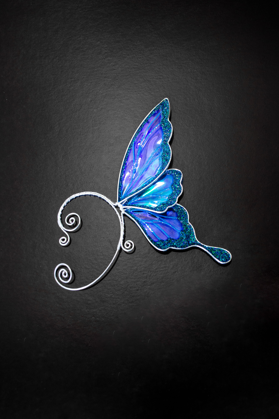Iridescent blue fairy wing ear cuff on black background