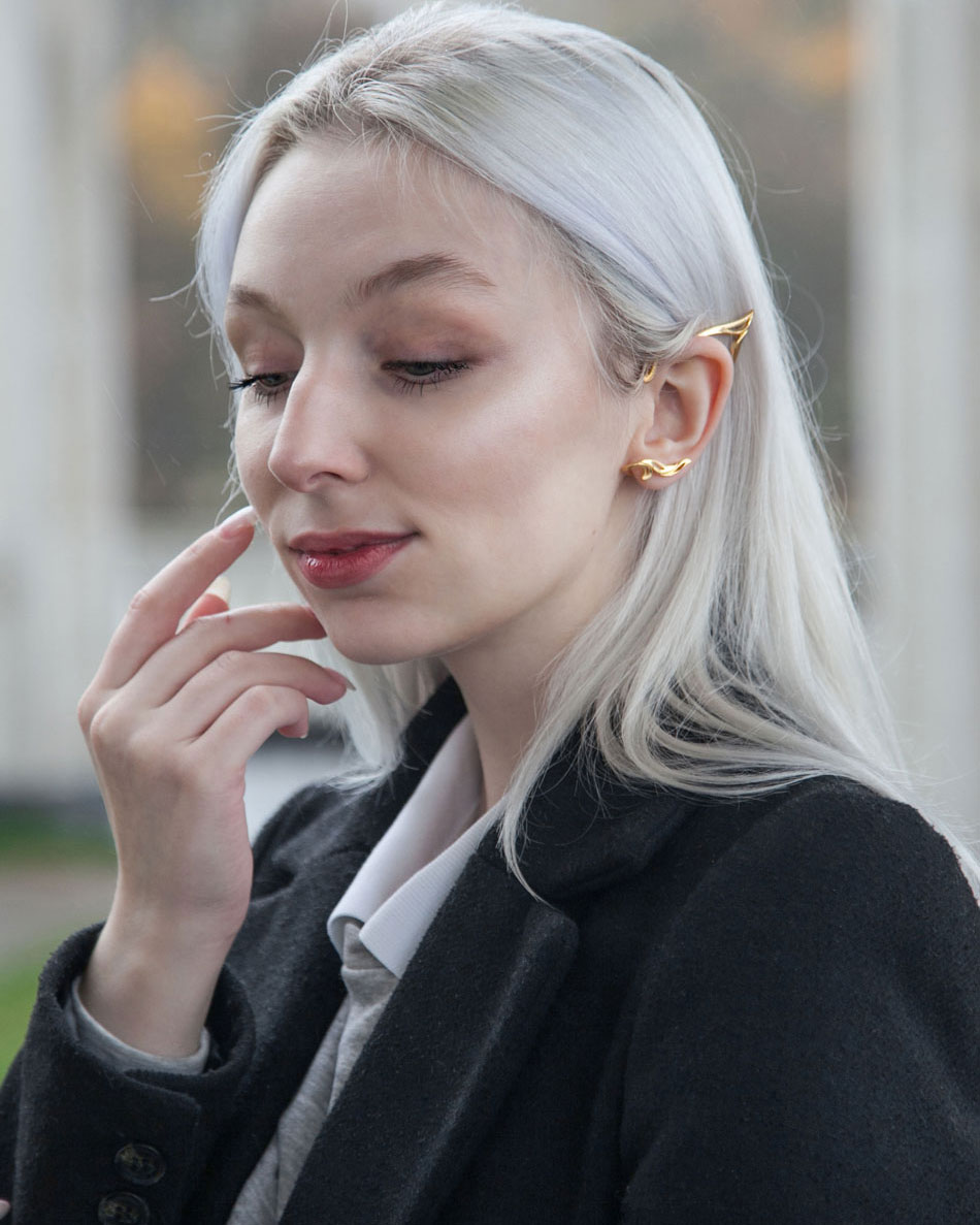 Model adjusting hair while wearing gold elf ear cuff