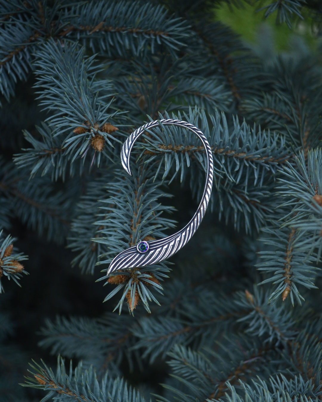 Silver elven ear cuff hanging on pine branches