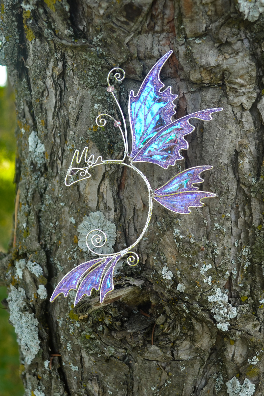 fairy dragon ear cuff on tree bark, handmade fantasy jewelry with dragon wings