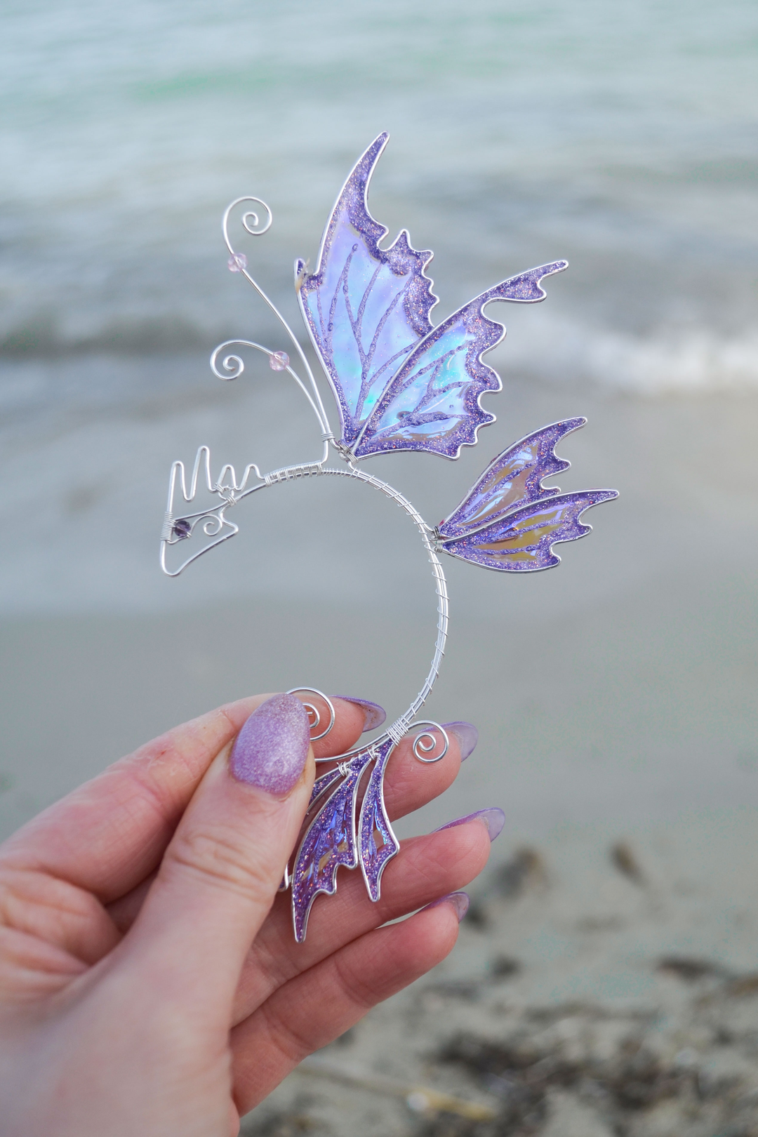 fairy dragon ear cuff held in hand by the sea, handmade fantasy ear cuff