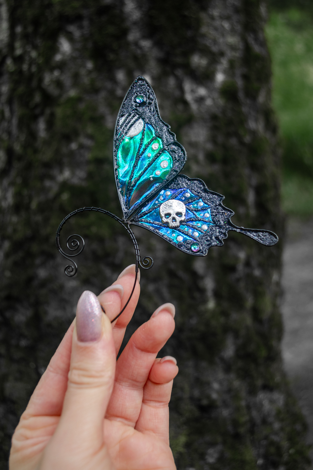 Gothic butterfly ear cuff with skull held in hand outdoors