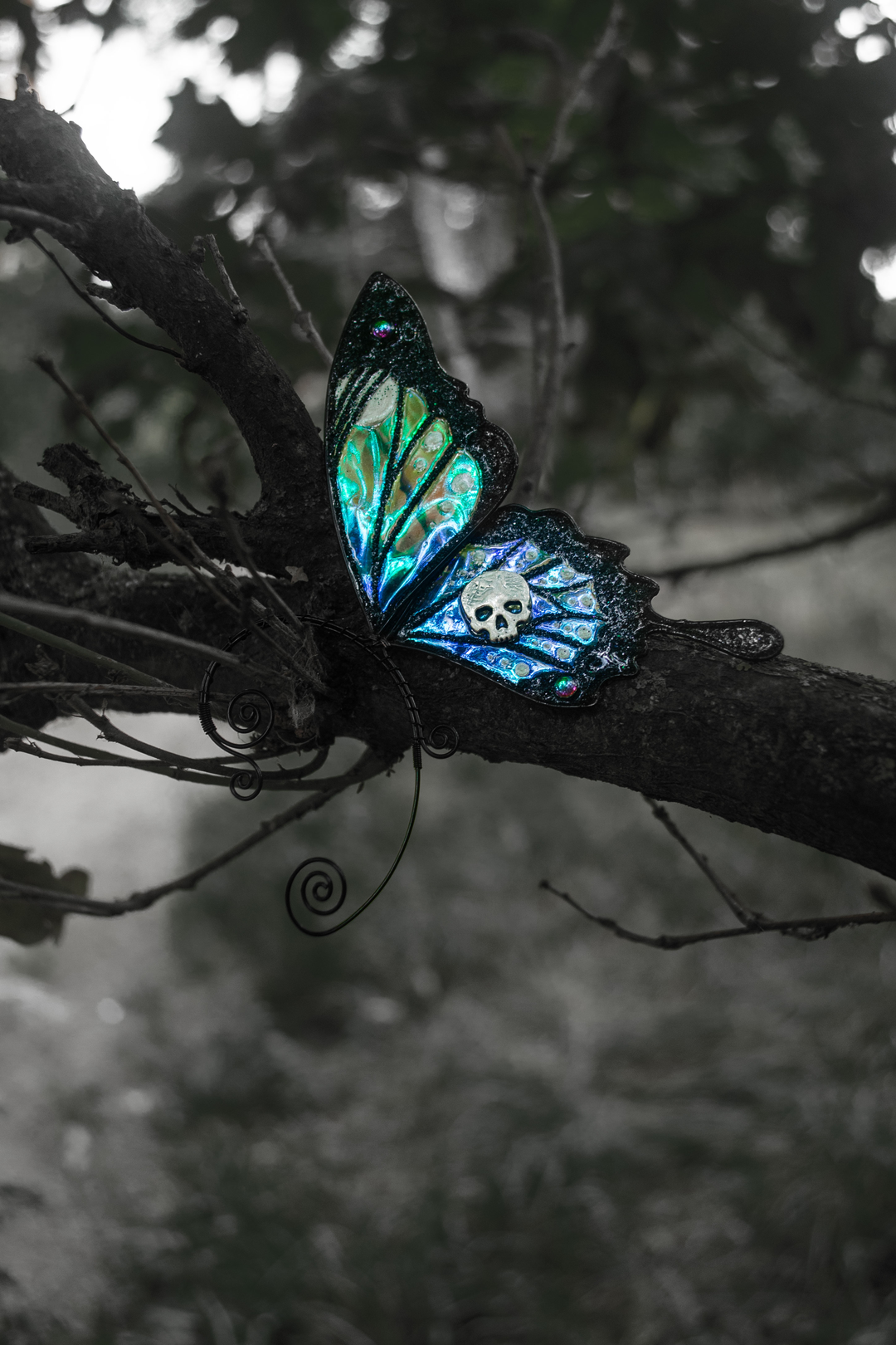 Gothic butterfly ear cuff with skull resting on a tree branch