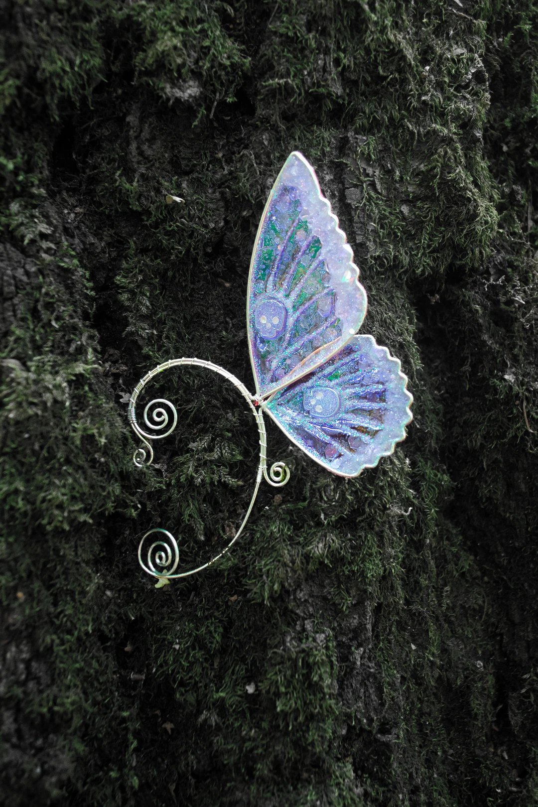 Blue butterfly ear cuff with skull close-up on moss