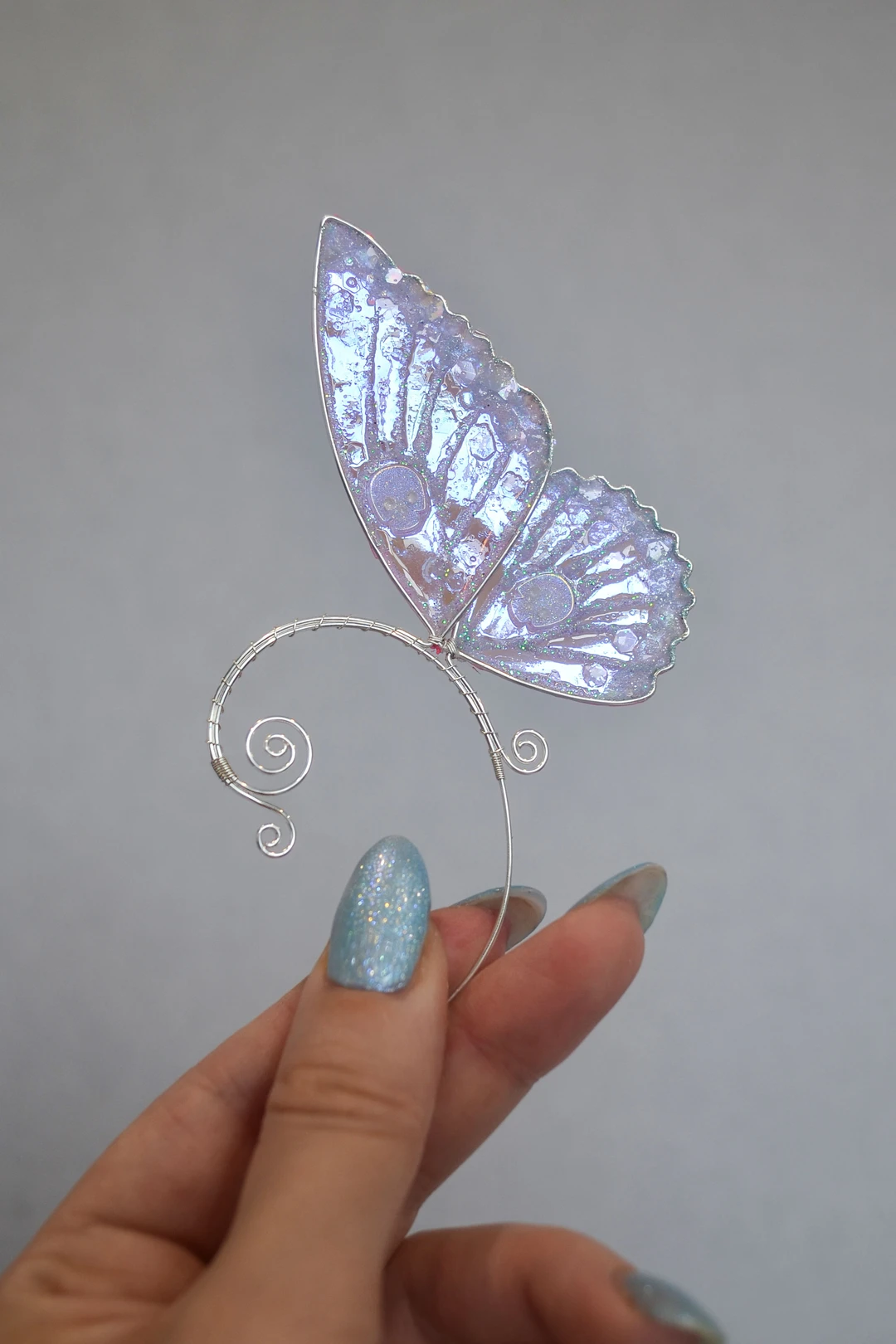 Blue butterfly ear cuff with skull held in hand
