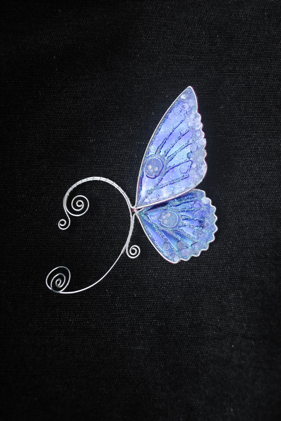 Blue butterfly ear cuff with skull on black background